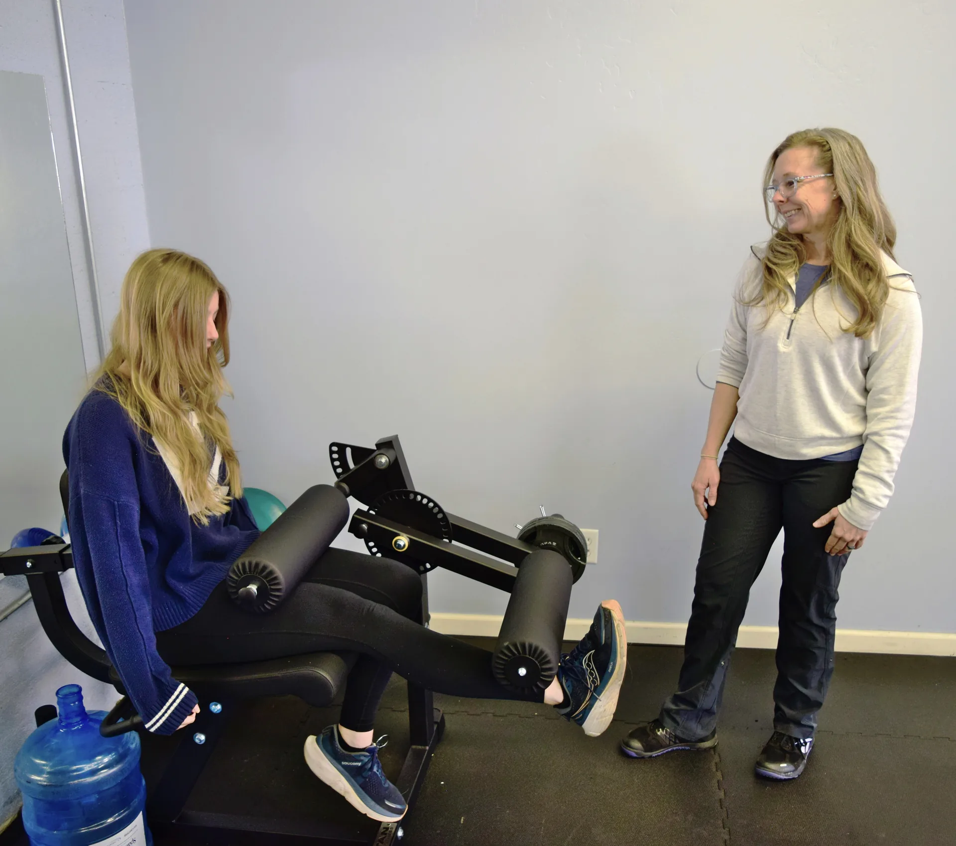 Dr. Crystal Geer coaching a patient through a leg press in the Proof Physical Therapy gym in Flagstaff