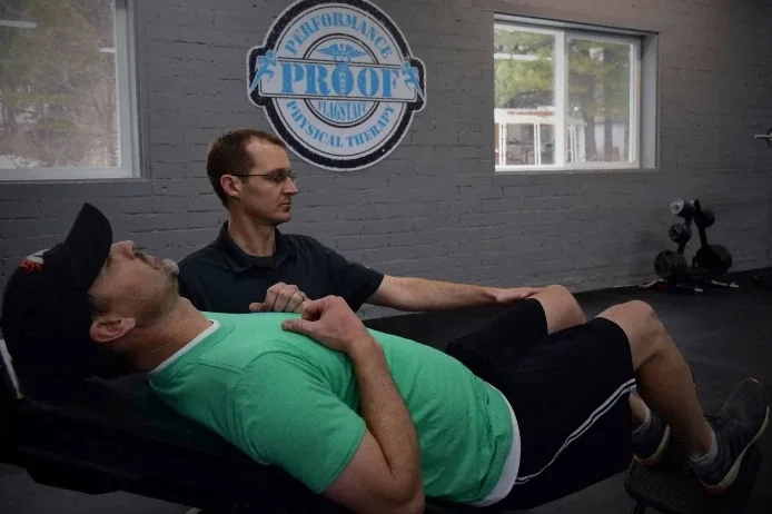 Dr. Jordan Williams treating a patient in front of the Proof logo on the clinic wall