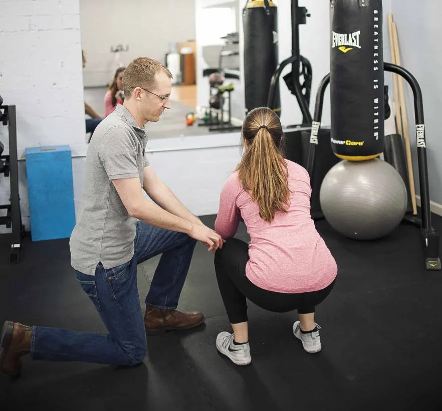 Dr. Jordan Williams coaching a patient's squat in the Proof gym