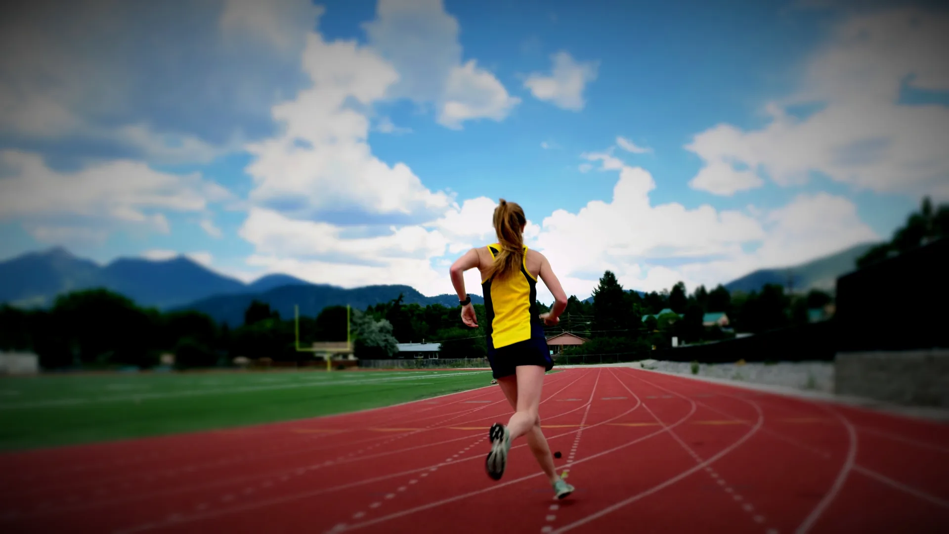 A runner on an outdoor track with the Flagstaff mountain skyline behind