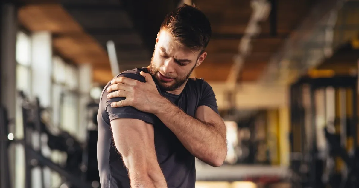Man in a gym gripping a painful shoulder