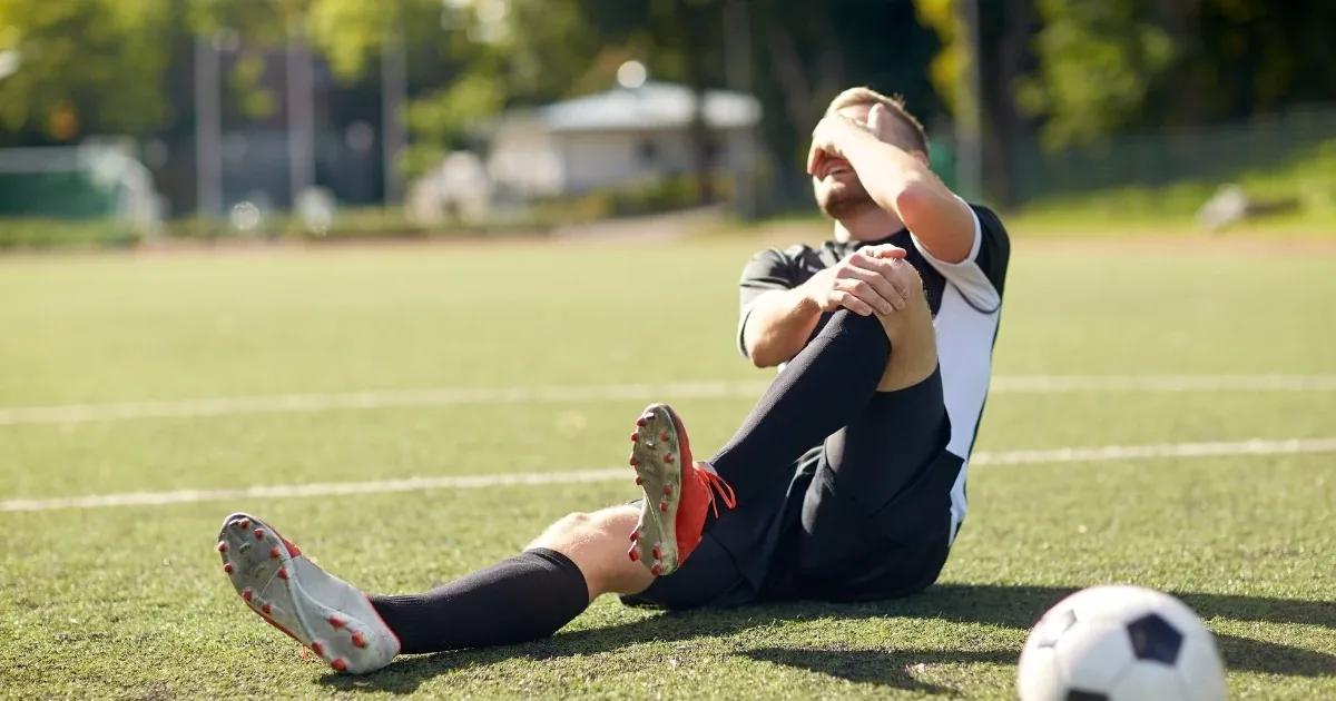 Athlete down on the field holding an injured knee